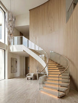 White oak veneer panels covering a sweeping curved wall beside a modern spiral staircase