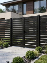 Black aluminum double gate with horizontal slats, center lock, and matching fence panels in a landscaped yard