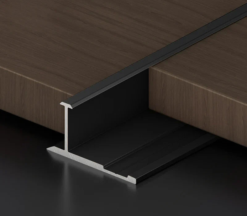 Black I-shaped aluminum wall panel trim sample positioned between wood-look panels