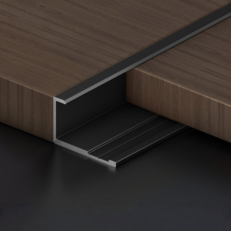 Black 3mm aluminum end cap trim fitted along the edge of a dark wood-look PVC wall panel