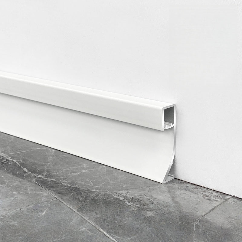 Close-up of white aluminum LED baseboard molding showing the open light channel beside gray tile flooring