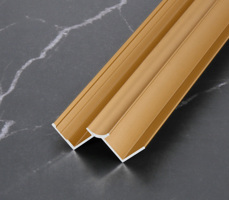 Gold 3mm aluminum inside corner trim profile close-up on dark marble