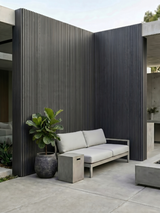 Gray composite wide exterior cladding covering tall courtyard walls behind a sofa and potted plant