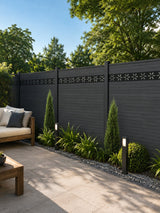 Modern decorative fence screen with floral cutouts installed along a dark garden fence beside a paved seating area