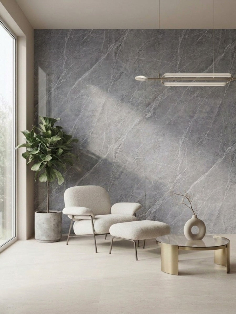 Ash gray marble PVC feature wall behind a cream lounge chair, ottoman, plant, and round table