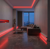 White aluminum LED baseboard molding casting red RGB light around a contemporary living room