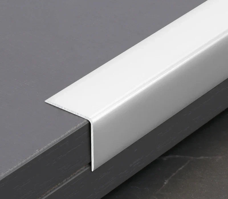 White L-shaped aluminum wall panel trim sample fitted over a panel edge