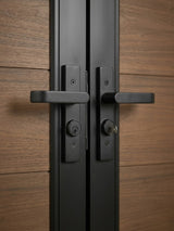 Close-up of black handles and keyed locks on the brown WPC double fence gate