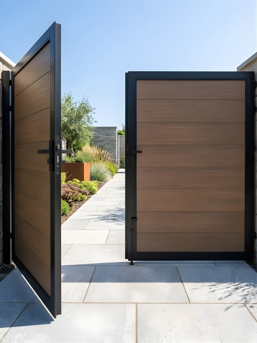 Brown WPC double fence gate open onto a paved landscaped garden walkway