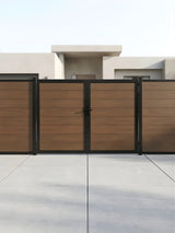 Closed brown wood-look WPC double fence gate across a modern paved entrance