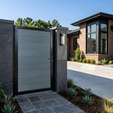 Gray WPC fence single gate installed between stone pillars at a modern home entrance