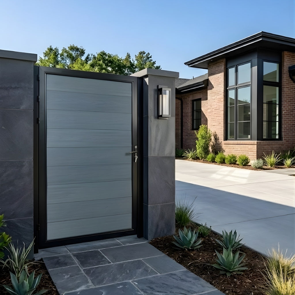 Gray WPC fence single gate installed between stone pillars at a modern home entrance