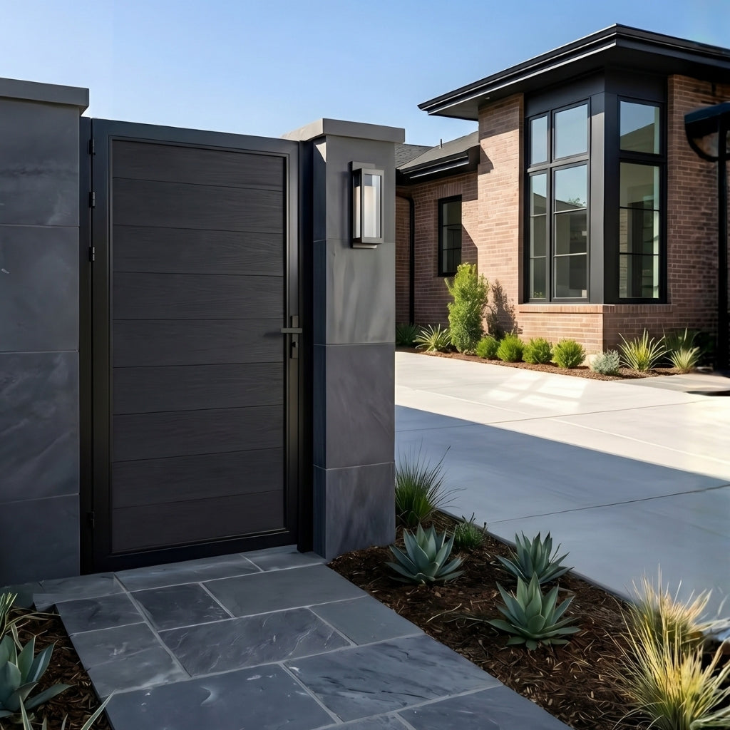 Closed black WPC fence gate at a modern home entrance with stone paving