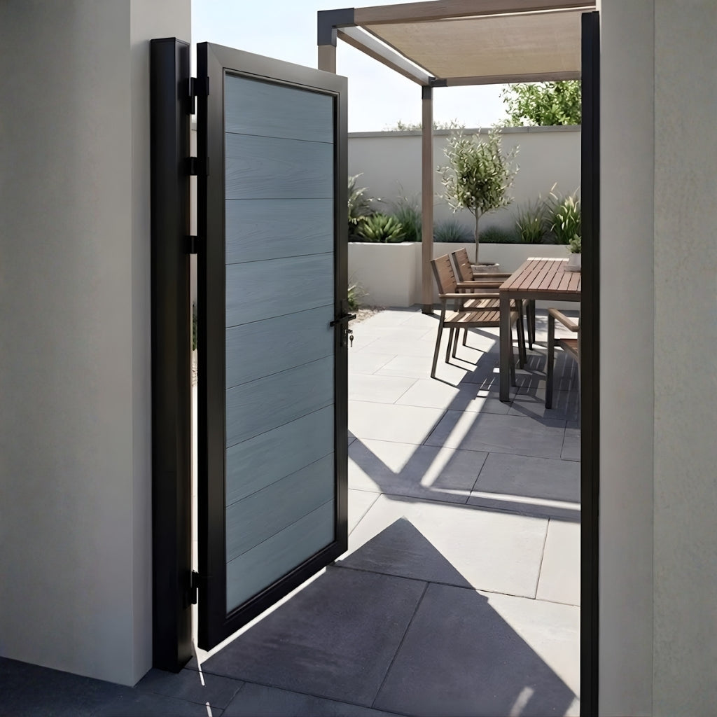 Open gray WPC fence single gate leading to a sunlit patio dining area