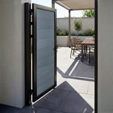 Open light gray WPC fence gate leading to a paved patio with outdoor dining furniture